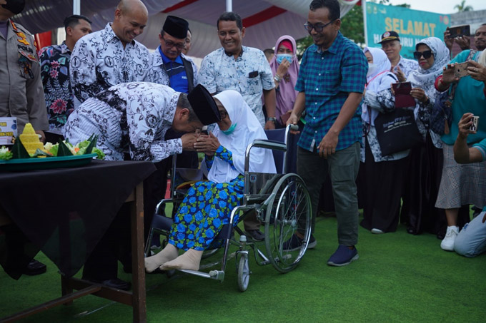 Gubernur Riau Syamsuar mencium tangan gurunya sewaktu SMP pada peringatan HUT ke-77 PGRI di Kabupaten Bengkalis, Sabtu (26/11/2022).